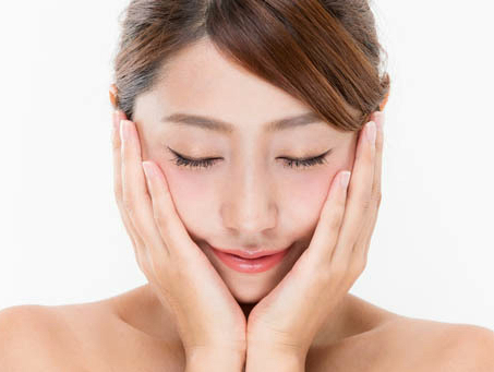 両手で顔を包み込みながら、リラックスした表情で肌ケアをする女性の写真