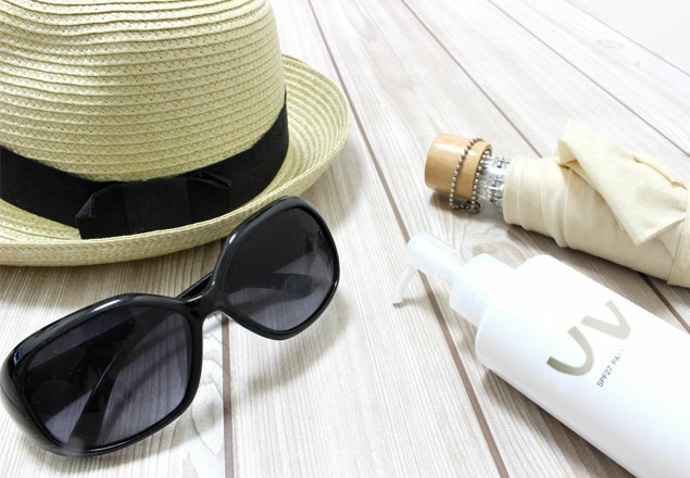 紫外線対策グッズとして並べられた夏用のパナマハット、サングラス、UVケアローション、日傘
