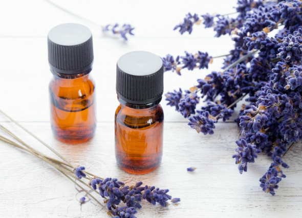 ラベンダーの精油ボトルとラベンダーの花が並ぶ写真。アロマを活用した安眠のイメージ